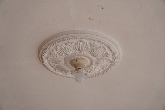 Decorative white ceiling rose with a vintage light fixture in a classic interior room.