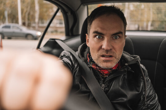 Furious male driver shouting and gesturing aggressively while sitting behind the wheel. Road rage, stressed driving, and angry reaction to traffic.