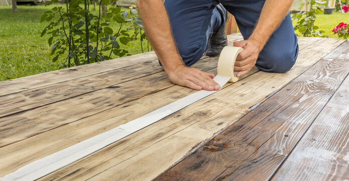 Worker tapes wood planks for deck repair