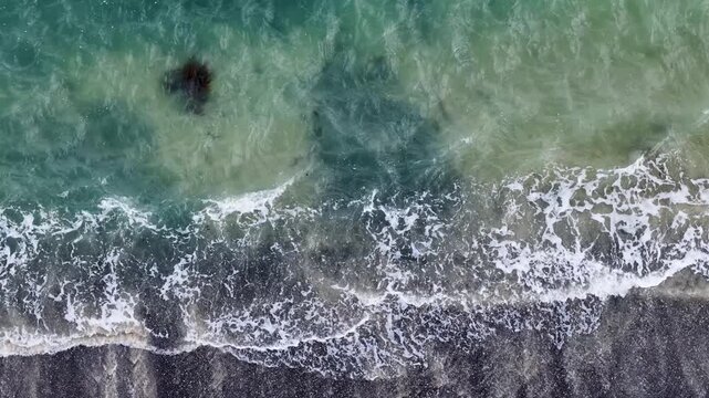 Aerial View of Turquoise Ocean Waves Crashing on Dark Sand Beach