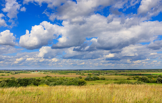 Sunlit meadow with rolling hills, fluffy clouds, and serene atmosphere