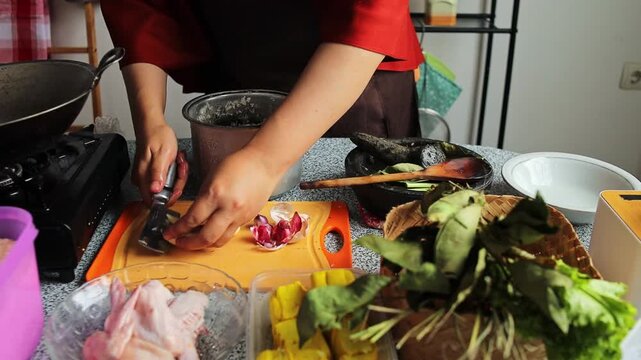 Chef slicing garlic and shallots on board to prepare delicious ingredients for cooking in kitchen