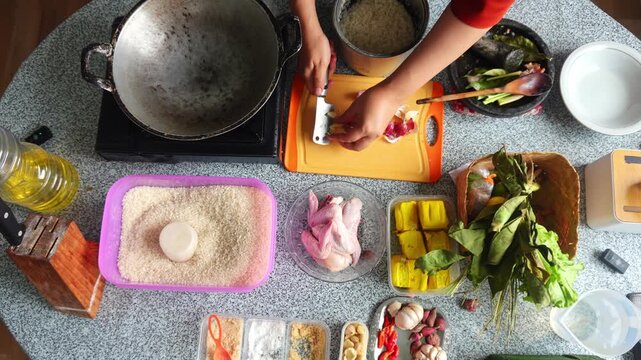 Top-down view of chef slicing shallots on orange board during meal prep with ingredients spread out