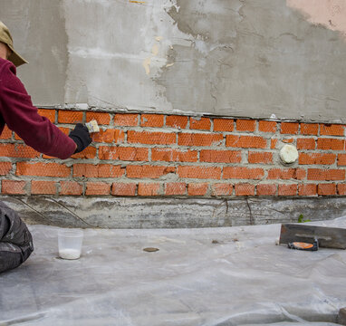 Construction worker applying mortar to red bricks