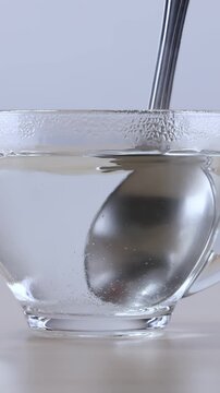 Metal Spoon Stirring Hot Water in Transparent Glass Cup