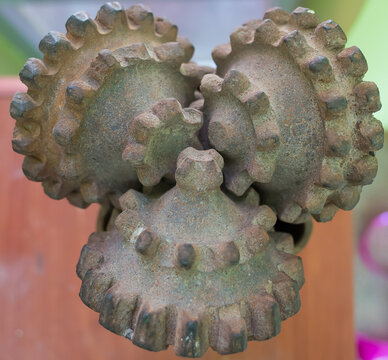 Close up of three textured metal gears in warm light against blurred wooden background, symbolizing industry and mechanics.