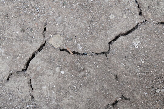 Cracked concrete texture background with weathered grey stone surface and deep fissures.