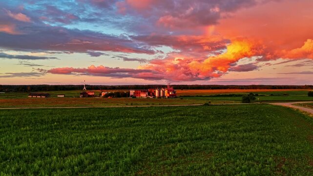 Epic vibrant sky with dramatic clouds moving over a grain elevator and a rural landscape