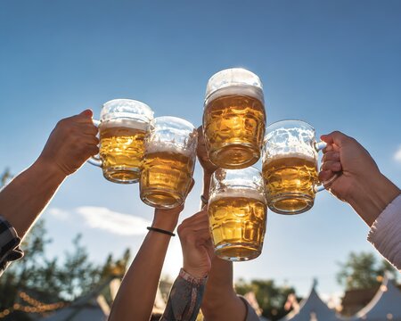 Friends Raising Beer Mugs Against Blue Sky at Outdoor Festival