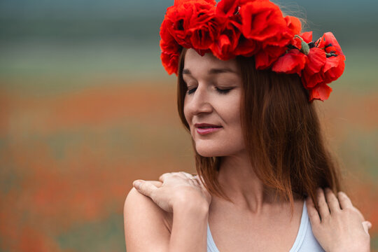 Woman poppy wreath closing eyes in a peaceful field of blooming red flowers