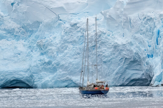 Antarctica, Antarctic Peninsula. In the Gerlach Street. Fournier Bay. Sailing boat surrounded by ice floes with the enormous Ice shelf in the background.