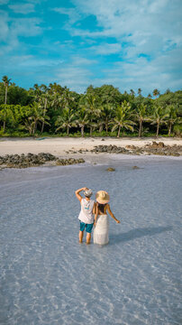 Couple tourist stay happy moment at the edge of the sea beach under shallow of the crystal clear water in summer trip on tropical island island