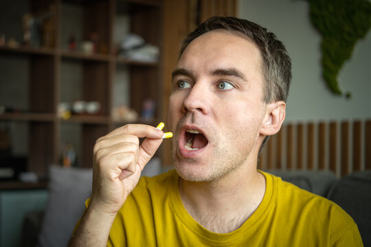 Close-up of a man swallowing two medicine capsules, illustrating daily medication, vitamin intake, self-care, and personal health management.
