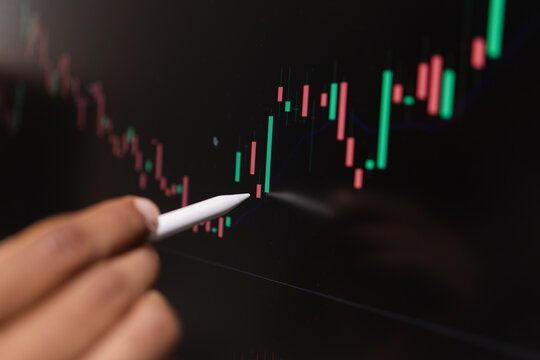Professional trader analyzing stock market charts on laptop, tablet, and monitor while reviewing candlestick patterns, technical indicators, and market trends to support informed investment decisions.