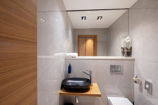 Modern compact bathroom interior with black bowl sink and large mirror