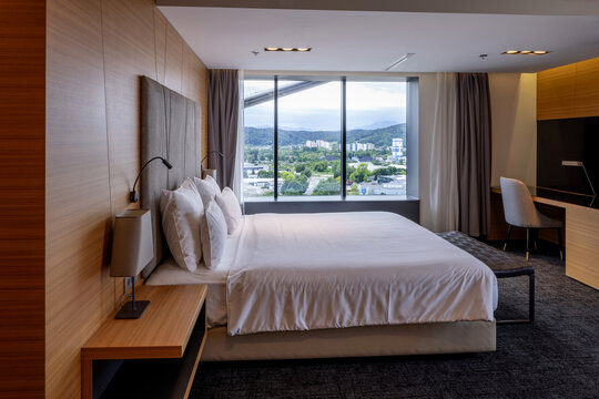 Modern hotel bedroom interior with king size bed panoramic view and desk