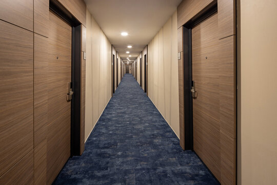 Long empty corridor in a modern luxury hotel with wooden doors and blue carpet