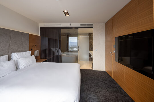 Luxury hotel suite bedroom with comfortable king size bed and glass bathroom partition