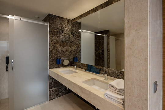 Modern luxury hotel bathroom with double vanity marble counter and mirror