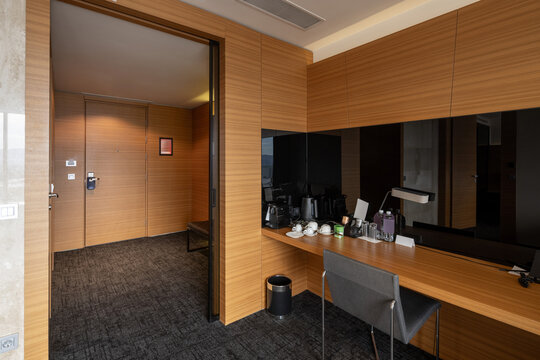 Modern hotel suite entrance area with wooden desk coffee setup and wardrobe