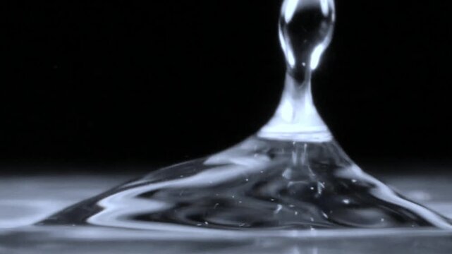 Dynamic water droplets splash and rebound from a smooth glass surface in macro detail.