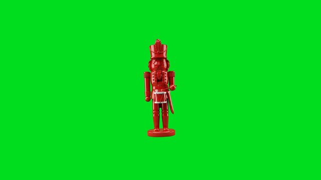 A vibrant red nutcracker figurine isolated against a bright green background