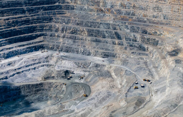 Fototapeta premium Haul trucks operating on terraced benches inside mine pit, industry diamond mining factory