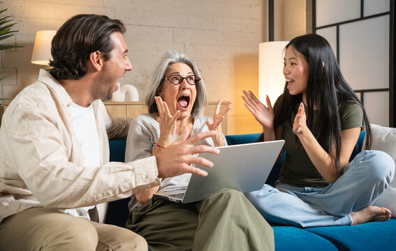Excited family members reacting with joy and surprise while looking at a laptop screen at home