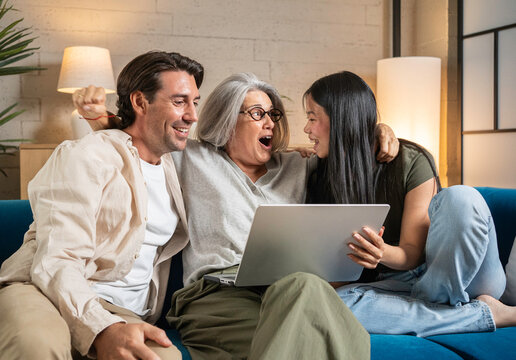 Happy multi-generational family celebrating success and watching exciting content on a laptop together