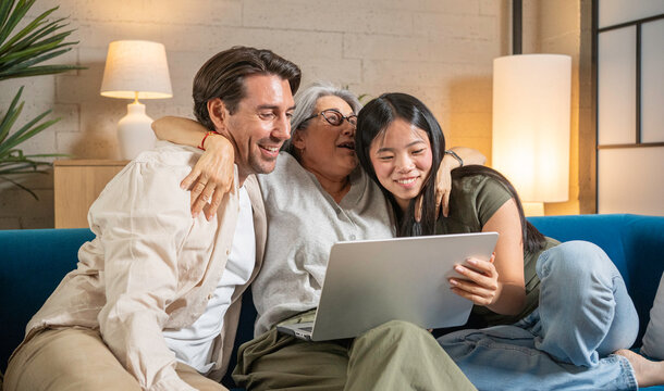Multi-generational family bonding at home while looking at a laptop screen