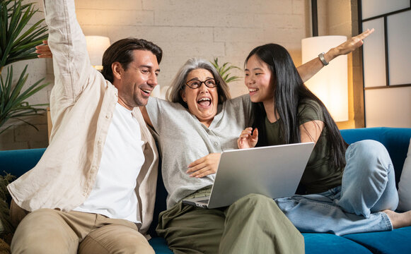 Happy family cheering, finding excitement while using a laptop on the couch