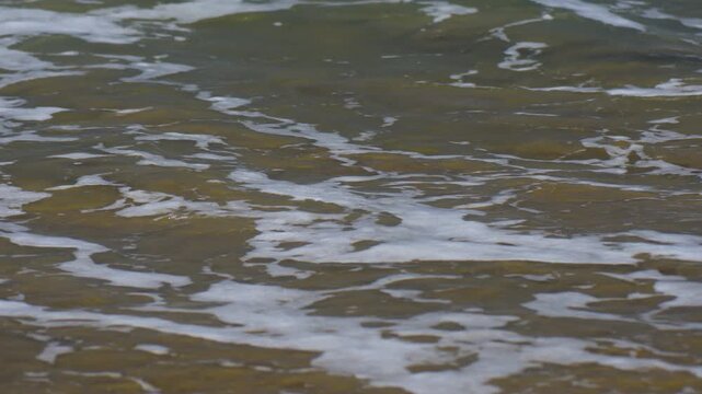 close up of waves washing over the sand at the beach