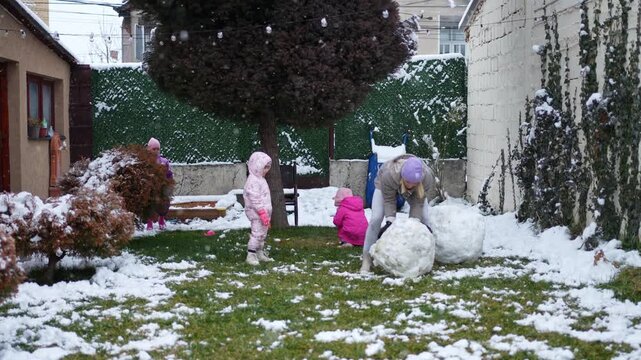 Children enjoy winter fun while building snowmen in a snowy yard