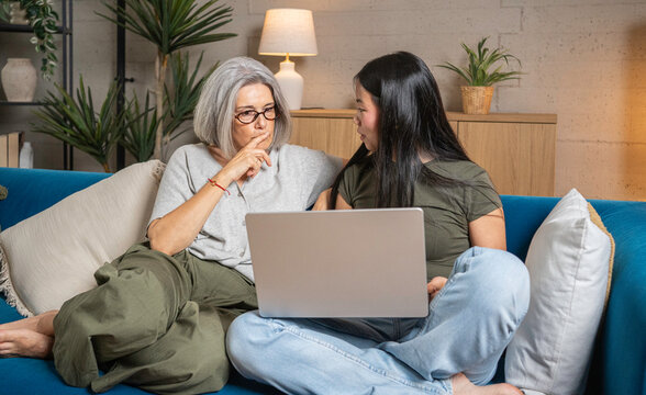 Two women of different generations discussing content on a laptop at home