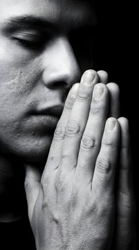 Retrato en blanco y negro de hombre joven rezando con las manos juntas y los ojos cerrados en actitud de fe y meditaci&oacute;n