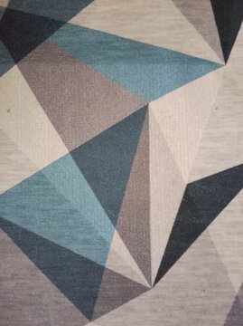 Modern geometric triangle pattern carpet texture in soft blue, gray, and beige tones for interior design background, floor covering, or textile wallpaper.