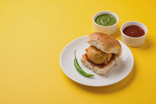 Indian Vada Pav with spicy chutneys and green chili on plate