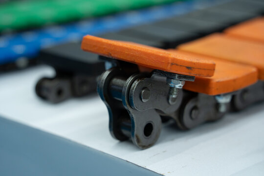 Close-up of Industrial Conveyor Chain with Orange Attachment Plates