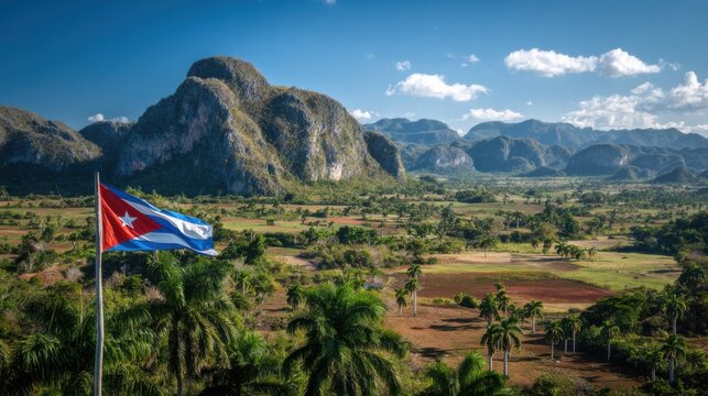 Cuban landscape with mountains, palm trees, flags, and blue skies on a sunny day in a rural area
