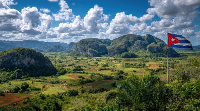 Landscape view of Cuban mountains under blue sky with clouds and a Cuban flag waving nearby