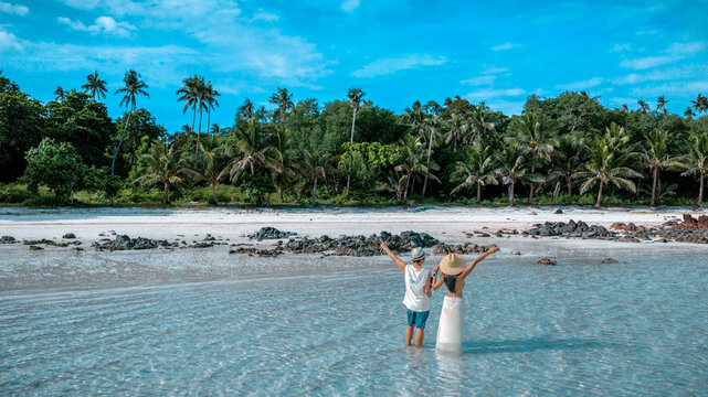 Couple tourist stay happy moment at the edge of the sea beach under shallow of the crystal clear water in summer trip on tropical island island