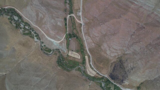 Close aerial of a winding green watercourse on Chalus Road cutting a dry mountain face, showing erosion channels and slopes. Ideal for travel, tourism, and nature stock Iran Alborz valleys.