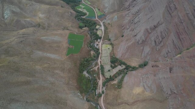 Chalus Road aerial shows dry mountain folds with isolated green field patches along a valley track through Iranian highlands. Ideal for travel, tourism, and nature stock Iran Alborz valleys.
