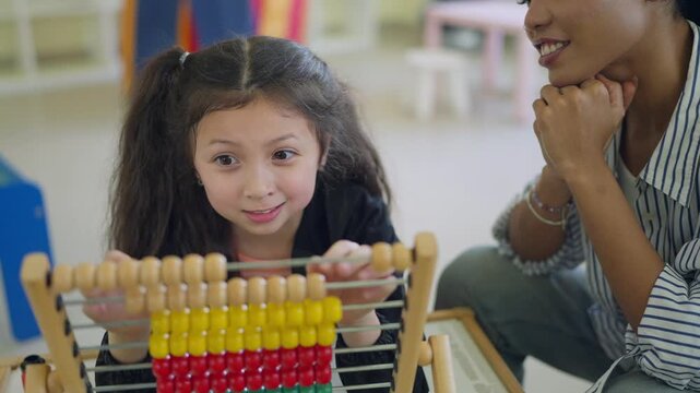 Young girl concentrates on colorful abacus with teacher beside her. Teacher smiles gently, guiding her through math learning