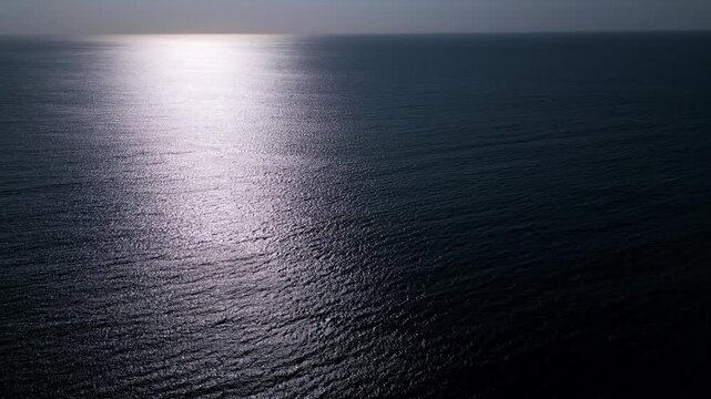 Aerial View of Calm Ocean Water Surface with Golden Sun Reflection at Sunset