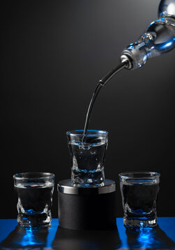Vodka pouring from the bottle into a glass on a dark background.