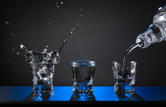 Barman pouring hard spirit into glasses.