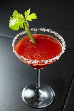 Bloody Mary cocktail with celery on a black background.