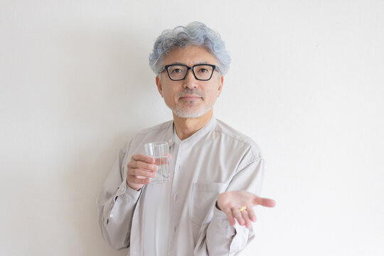 水と薬を手に健康管理をするシニア男性
