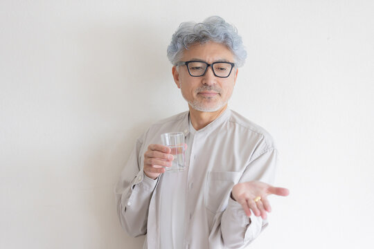 水と薬を手に健康管理をするシニア男性
